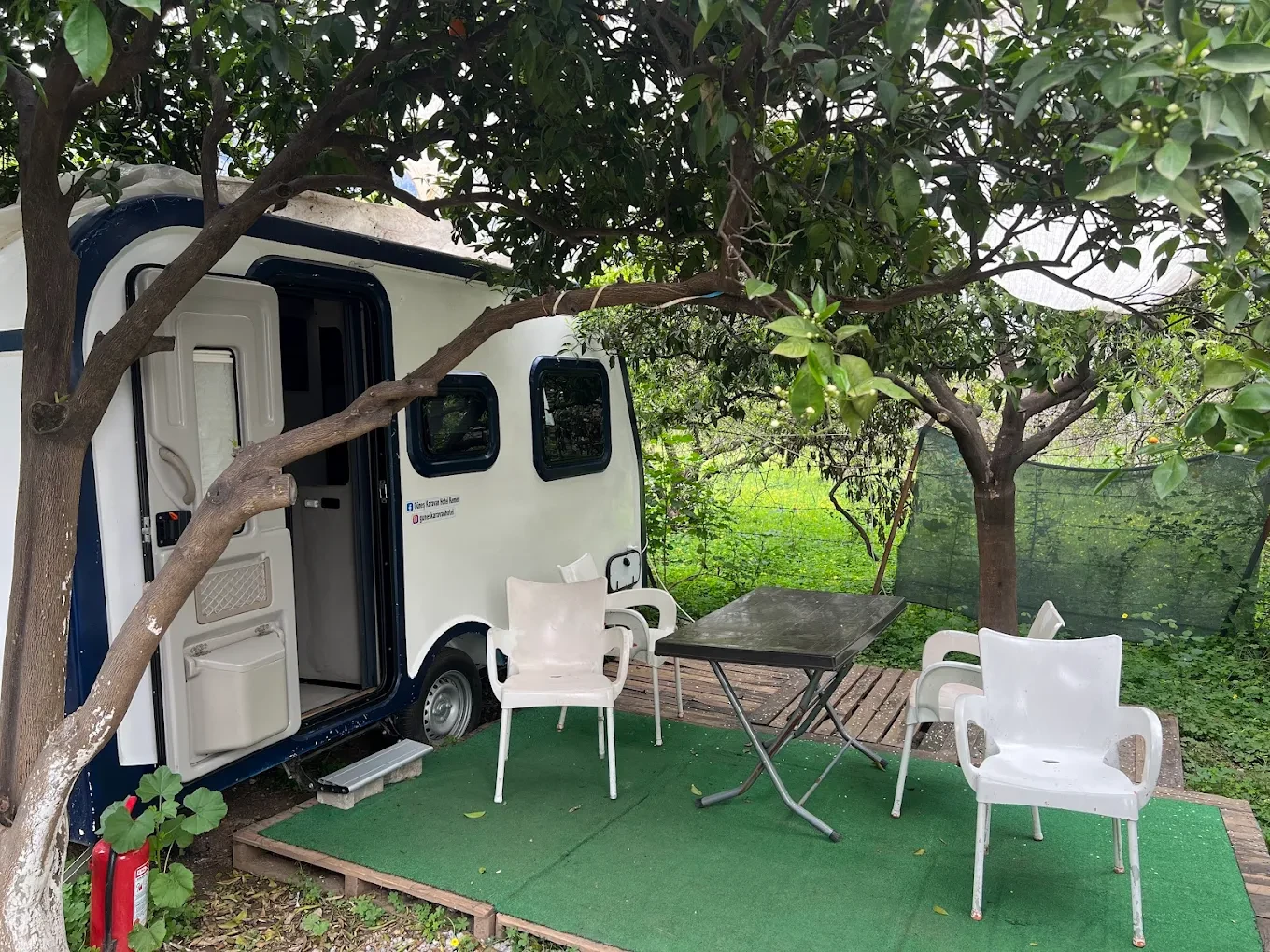Ağaç altındaki beyaz karavan ve masa