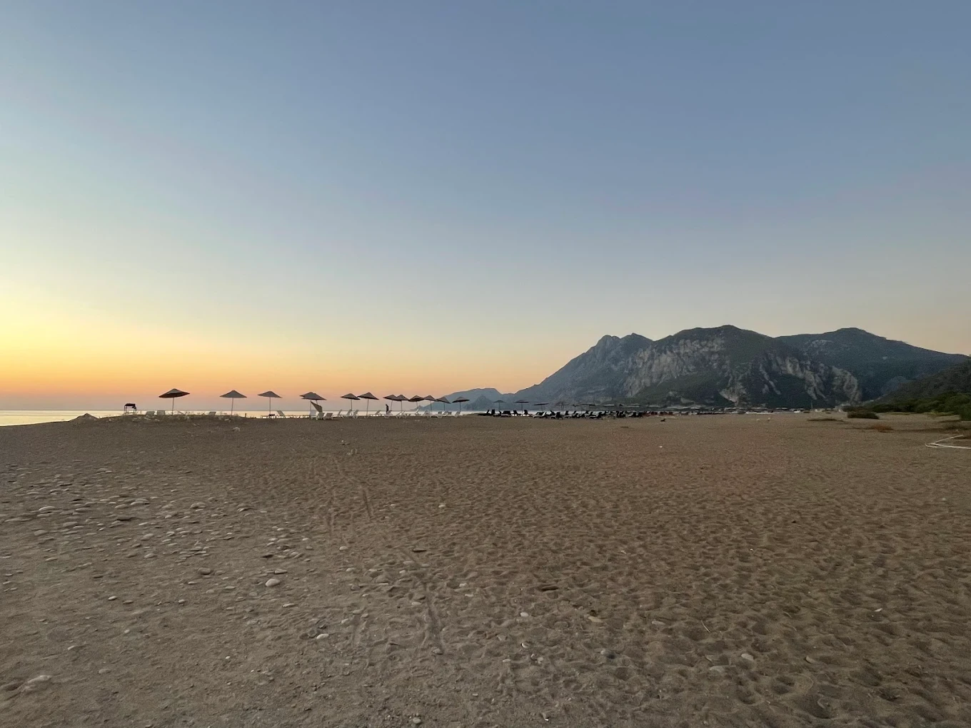 Plaj şemsiyeleri ve dağ manzarası